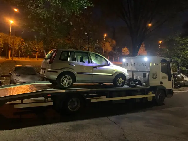 Zeleni automobil na platformi šlep vozila, noćna intervencija pod uličnim svetlom