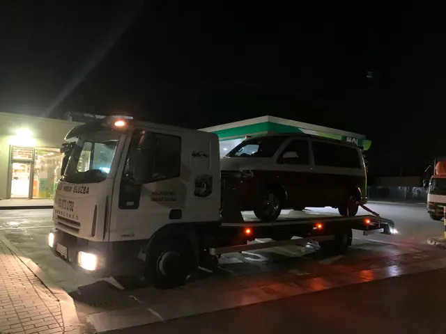 Kombi na platformi šlep vozila ispred benzinske pumpe noću