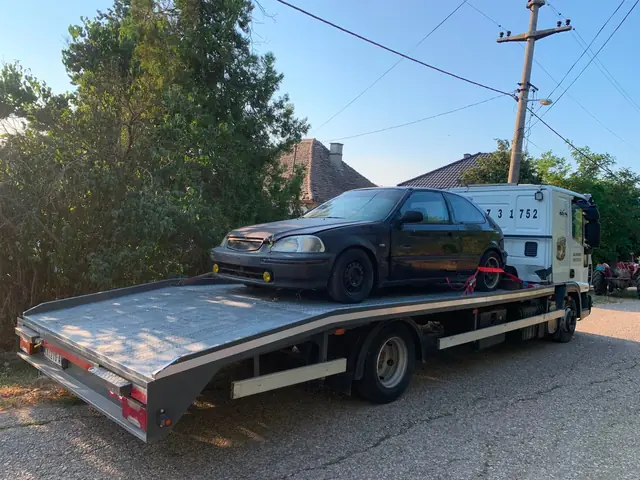 Tamni automobil na spuštenoj platformi šlep vozila