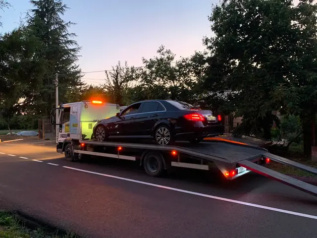 Automobil na platformi sa upaljenim rotacionim svetlima u sumrak